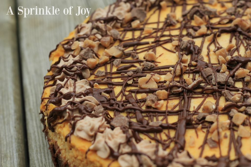 Pumpkin Cheesecake with Brownie Bottom| Are you looking for a different twist on pumpkin. Try this yummy pumpkin cheesecake made with a brownie layer on the bottom, drizzled with chocolate and topped with toffee pieces. From https://www.asprinkleofjoy.com/recipe/pumpkin-cheesecake-brownie-bottom/