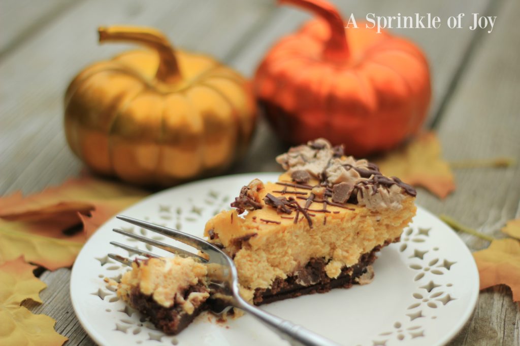 Pumpkin Cheesecake with Brownie Bottom| Are you looking for a different twist on pumpkin. Try this yummy pumpkin cheesecake made with a brownie layer on the bottom, drizzled with chocolate and topped with toffee pieces. From https://www.asprinkleofjoy.com/recipe/pumpkin-cheesecake-brownie-bottom/