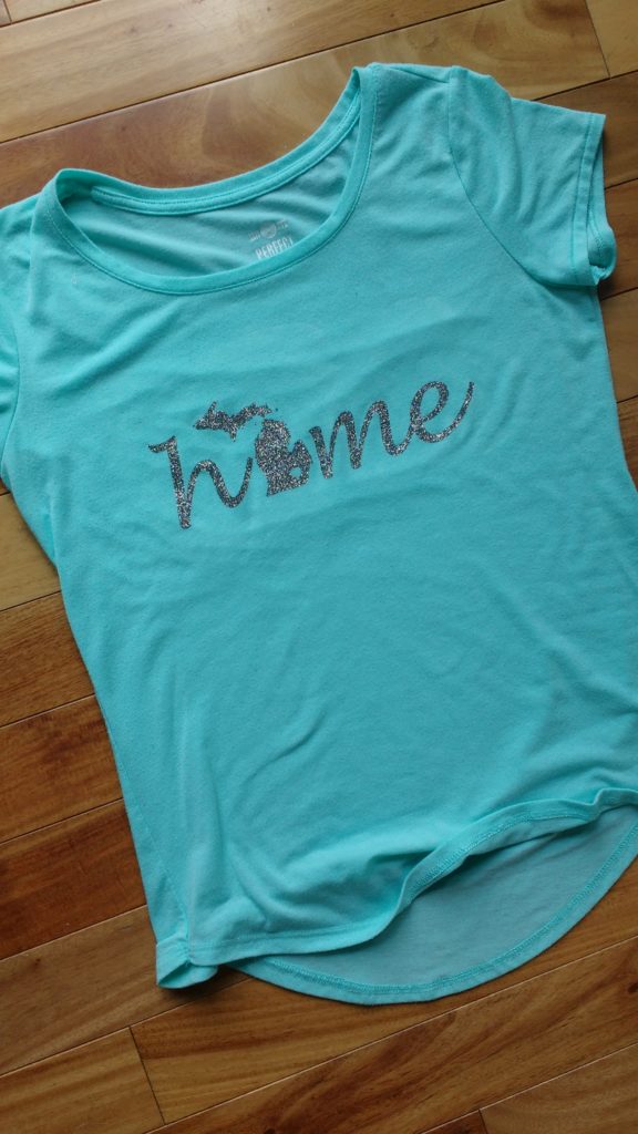 T-shirt with the word home, where the o is the shape of Michigan using heat transfer vinyl.