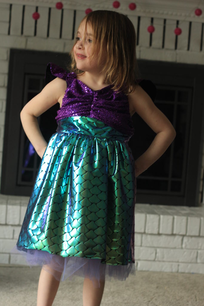 Little Mermaid inspired dress on young preschool girl, with her hands on hips. 