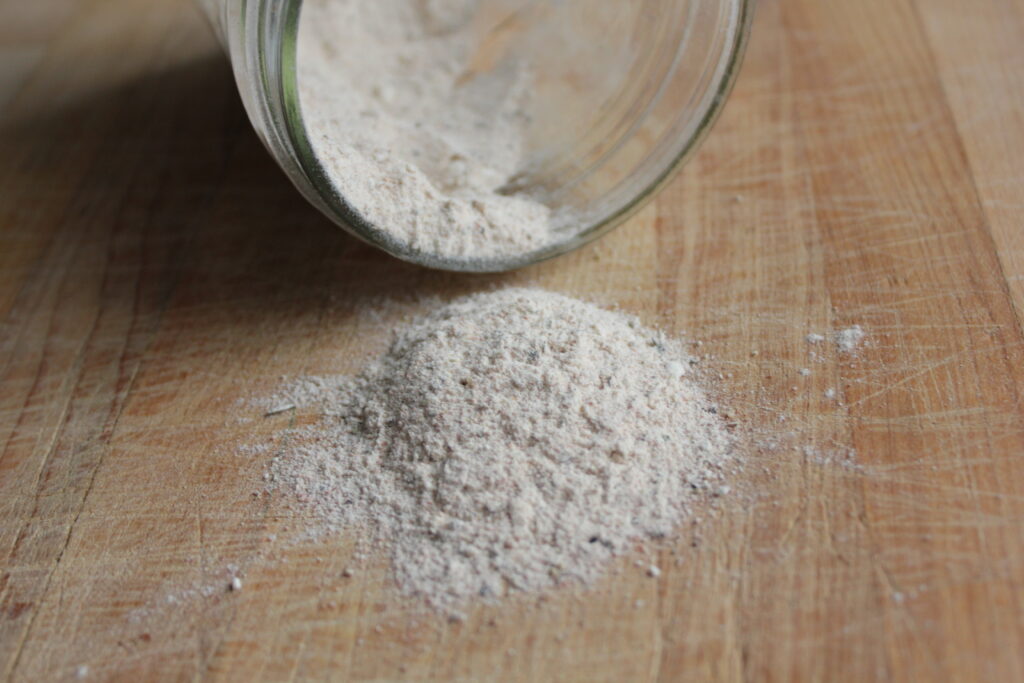 Finished beef stew seasoning blend pouring out of a glass jar