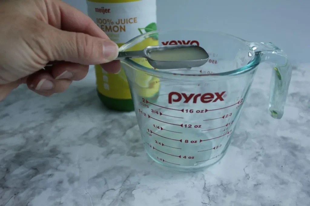 adding lemon juice to measuring cup